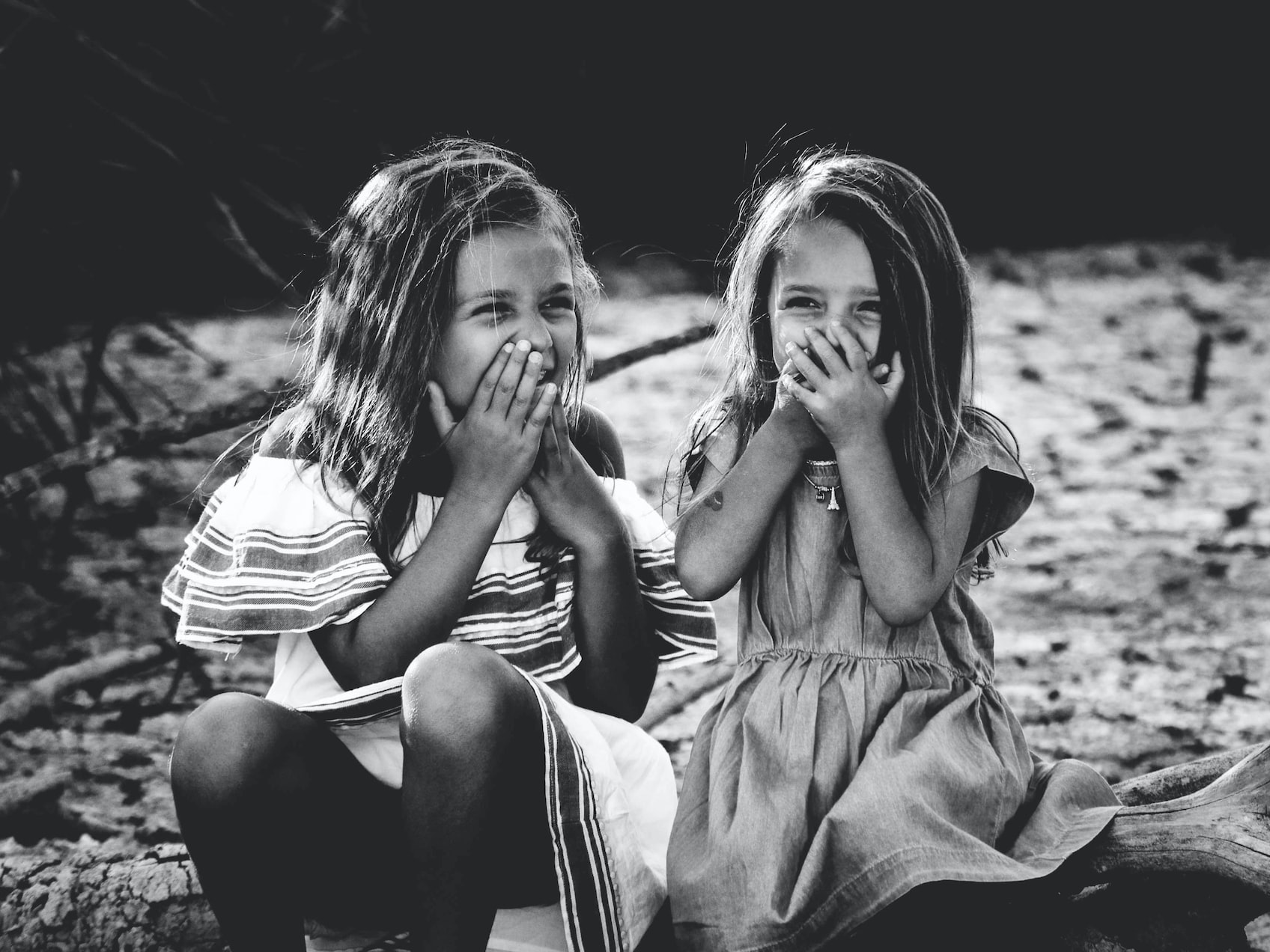 grayscale photography of two girls closing their mouths